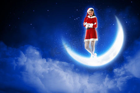 坐在月亮上的圣诞老人女孩的照片