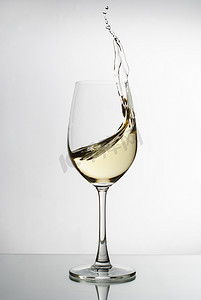 白葡萄酒从优雅的酒杯中飞溅