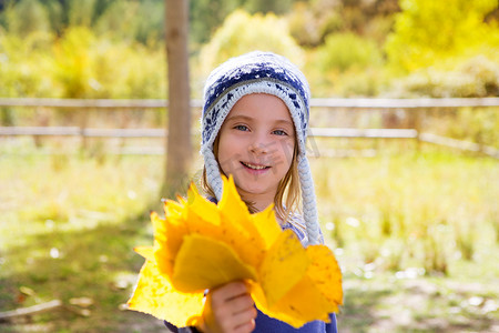 秋杨树林中的小女孩手里拿着黄落叶