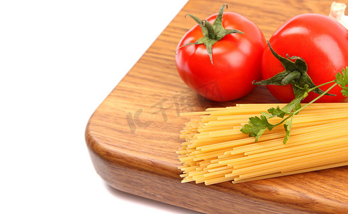 准备板上未煮过的意大利面、大蒜和西红柿位于左侧