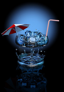 装冰块的杯子摄影照片_与冰块、伞和秸杆的鸡尾酒