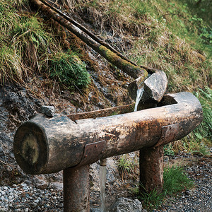 托木尔摄影照片_从山上的木喷泉流出的天然水