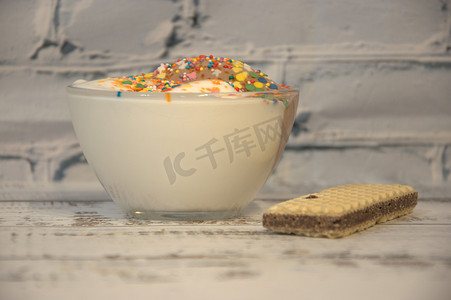冰淇淋设计摄影照片_木桌上放着一杯散落的冰淇淋和一只 vyflya。