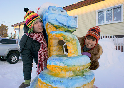 雪街道摄影照片_在雪雕附近的女孩。