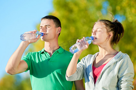 喝水的男人摄影照片_男人和女人从瓶子里喝水