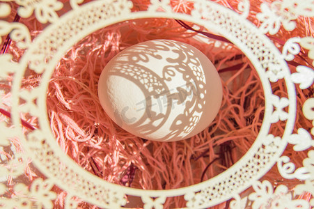 珊瑚背景上带蛋和白色镂空椭圆框的复活节贺卡，明亮的阳光在白蛋上营造出美丽的阴影，复制空间