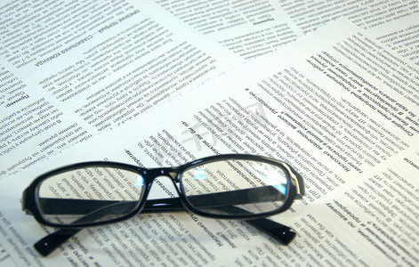 黑框眼镜躺在杂志的页面上。
