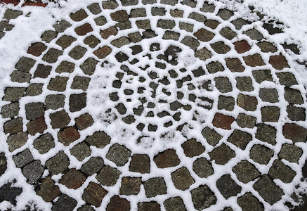 圆传统纹理摄影照片_冬天，一条古老的鹅卵石路上的白雪表面。