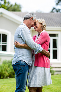 人在房子里摄影照片_快乐的老年夫妇站在院子里的房子外面