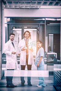 拿着数字平板电脑的医生与同事站在一起