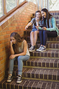 欺负人摄影照片_学校朋友在学校走廊欺负一个悲伤的女孩