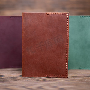 棕色的钱包摄影照片_生姜色手工皮革护照封面模糊的木制背景。