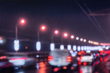 移动的汽车和灯笼的模糊灯光反射在夜城潮湿的沥青上。