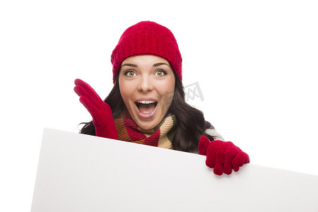 戴手套冬天摄影照片_惊讶的女孩戴着冬帽和手套举着空白牌子