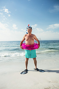 穿着充气环和脚蹼的快乐老人站在沙滩上