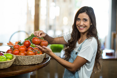 微笑的女人从篮子里摘新鲜西红柿