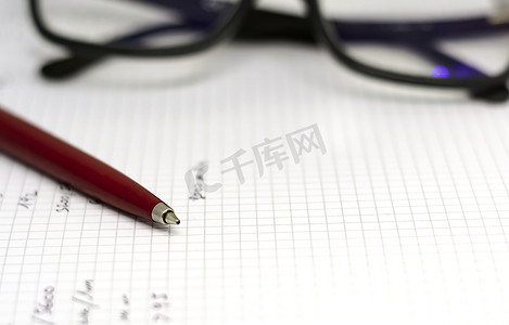 日记页摄影照片_打开的笔记本白页上的红色圆珠笔，背景是一副眼镜