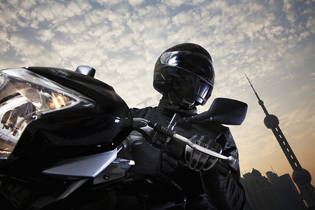 白天骑摩托车的年轻人，背景是天空和建筑外墙