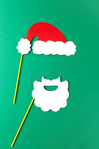 圣诞老人白胡子摄影照片_圣诞装饰、白胡子和红色圣诞老人帽子在棍子上。