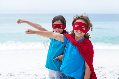 超级英雄摄影照片_在海滩穿超级英雄服装的兄弟姐妹