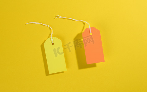 黄色背景上带白绳的空白矩形纸黄色和橙色价格标签