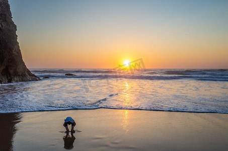 一个男孩在日落时在 Praia da Adraga 玩耍