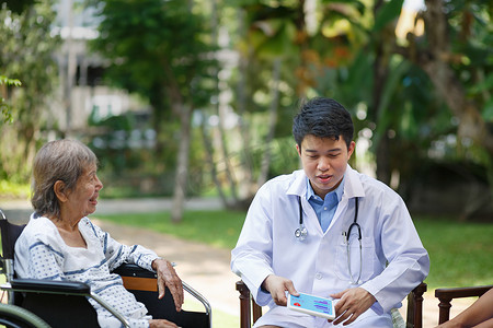 轮椅印摄影照片_亚洲医生与坐在轮椅上的老年女病人交谈
