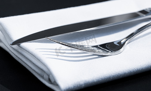 户外豪华餐厅的桌上放着白色餐巾的叉子和刀子，婚礼或活动的精美菜单以及餐饮服务理念