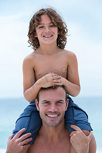 微笑的父亲背着儿子在海滩上