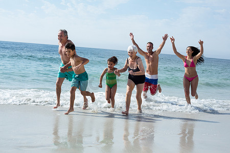 多代家庭在海滩上奔跑