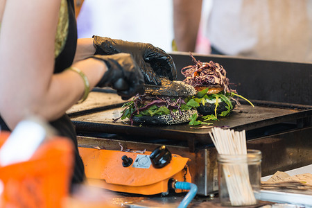 地中海老头摄影照片_厨师在开放式厨房国际美食节活动中在户外制作牛肉汉堡。