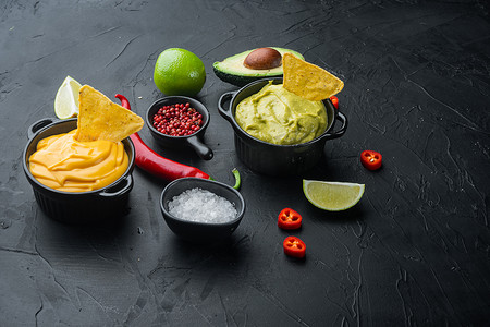 传统墨西哥炸玉米饼的绿色鳄梨酱和黄色奶酪蘸酱，黑色背景，带文本复制空间