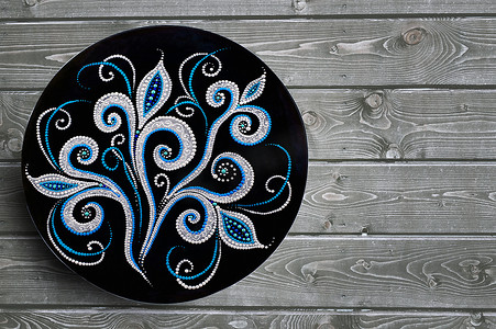 装饰陶瓷板手绘点图案与灰色木制背景上的丙烯酸涂料。
