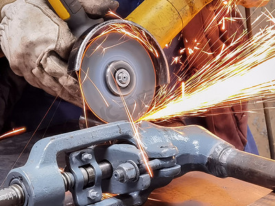 在室内制造重工业工厂使用平滑设备进行钢金属、铁、火花的研磨工作。