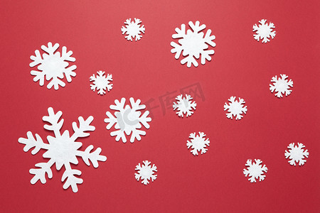 圣诞作文，勃艮第红色背景上的一组大大小小的白色毛毡雪花。