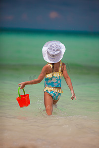 桶装水铁架摄影照片_小女孩在沙滩上玩耍，用桶装水