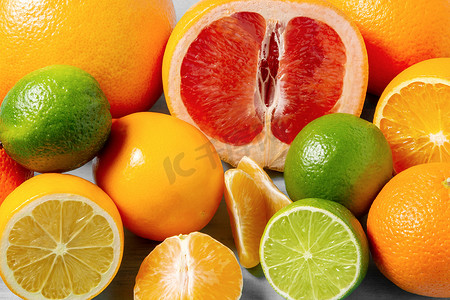 柑橘类水果摄影照片_一组完整和切片的柑橘类水果 — 桌子表面的橘子、柠檬、酸橙、橙子、葡萄柚 — 图片