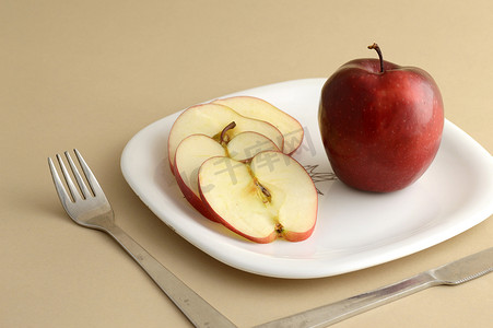白汁河豚摄影照片_美味的苹果和切片在白盘子里用刀叉