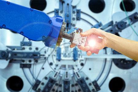 工业机器人与人握手，在概念工业 4.0 中从事工业制造，在蓝色调背景下工作的耀斑过滤器和模糊机械