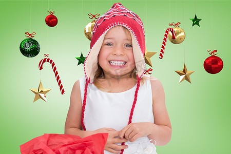 微尔摄影照片_戴着针织羊毛帽的快乐女孩对着数字生成的圣诞装饰微笑