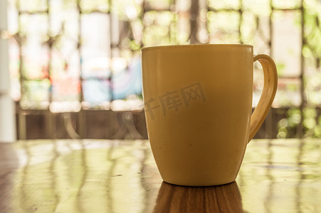 一杯卡布奇诺咖啡、摩卡咖啡、拿铁咖啡、美式咖啡、浓咖啡热咖啡香气的特写图像，在咖啡馆的质朴木桌背景上，背景是早晨从窗户射进来的阳光。