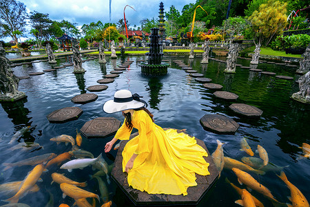 印度尼西亚巴厘岛 Tirta Gangga 水宫的池塘里喂养五颜六色鱼的妇女。