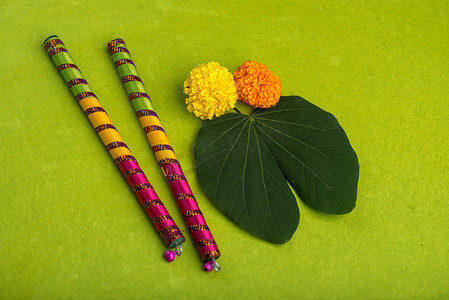 印度节日 Dussehra 和 Navratri，在绿色背景上展示金叶（Bauhinia racemosa）和万寿菊花以及 Dandiya 枝条