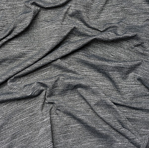 黑色杂色背景摄影照片_用于缝制衣服的灰色合成杂色织物，织物起皱