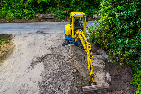 带沙子堆的黄色挖掘机，土方工业，移动沙子的挖掘机