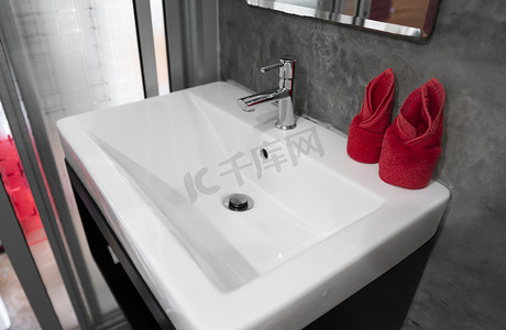 陶器摄影照片_带洗脸盆水槽的现代不锈钢龙头，上面有两条红色毛巾。