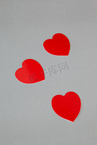 节日红色创意摄影照片_灰色背景中的三颗红心