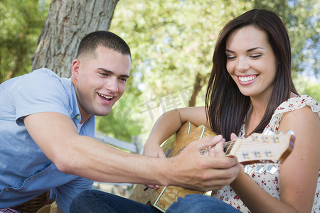 英俊的年轻人教混血女孩弹吉他