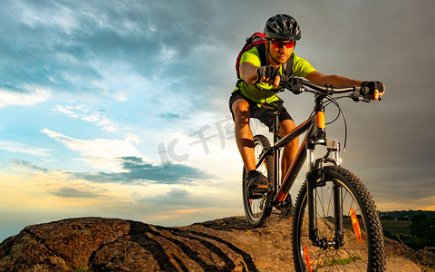 骑自行车的人在日落时分在岩石小径上骑自行车。