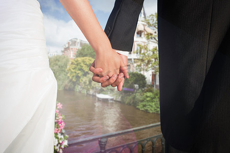 可爱的年轻新婚夫妇手牵着手的特写合成图像